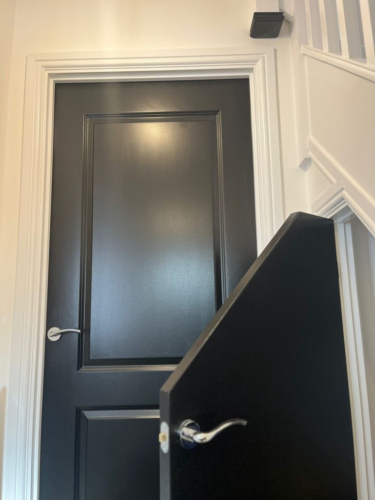 Black painted doors with a silver handle, located at the top of stairs.