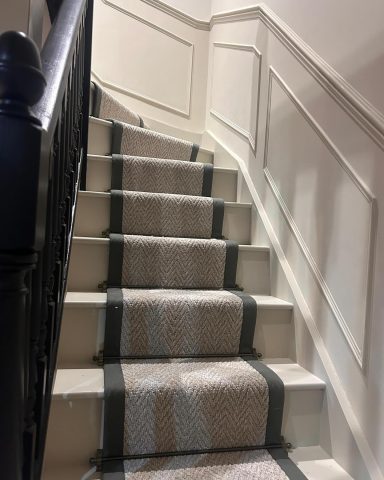Carpeted staircase with a patterned runner and dark wooden railing.