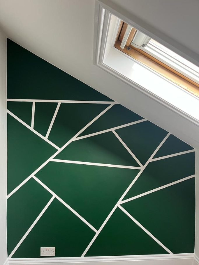 Geometric green wall design with white lines forming triangular patterns.