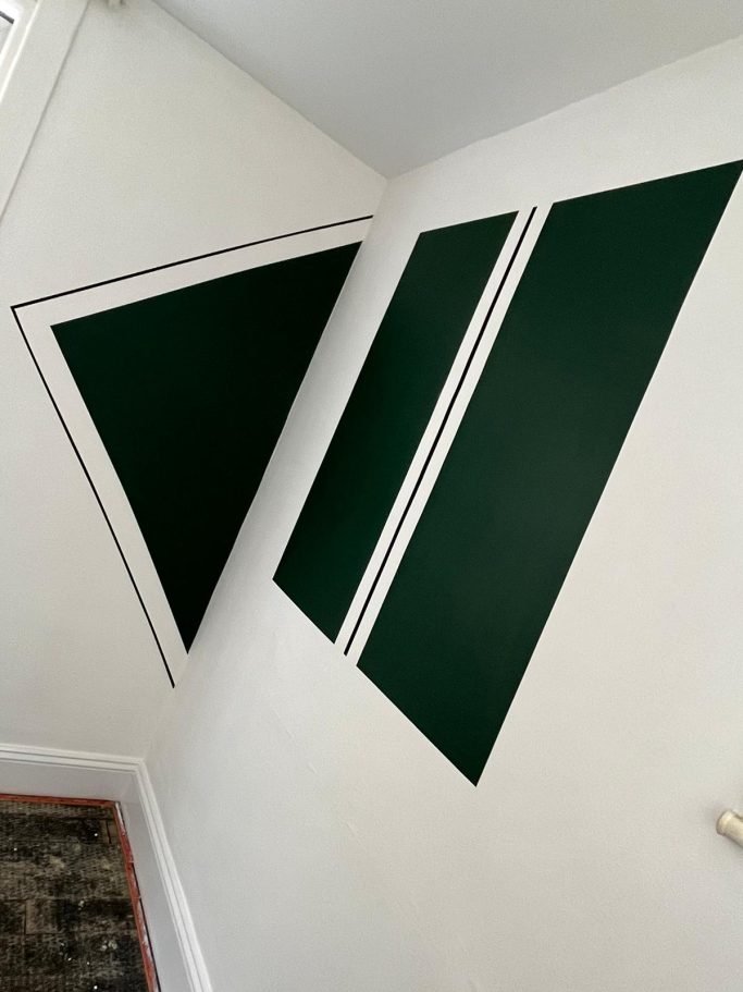 Interior wall with two green shapes, one triangular and one rectangular, on a white background.
