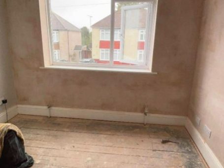 Empty room with bare floorboards and freshly plastered walls