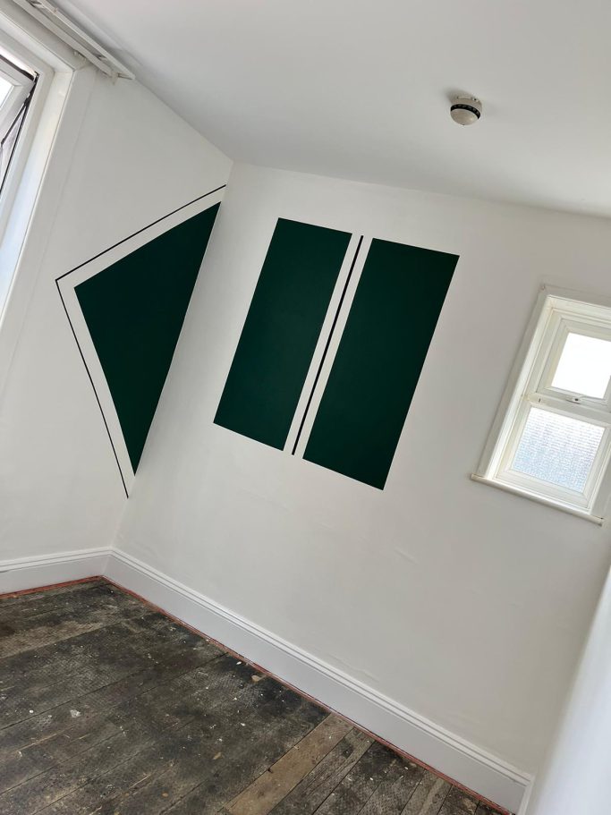 Interior corner of a room featuring two vertical green panels on white walls.