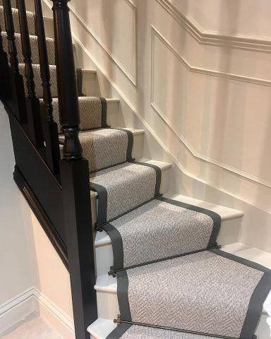 Staircase with beige carpet and black bannister leading upwards.